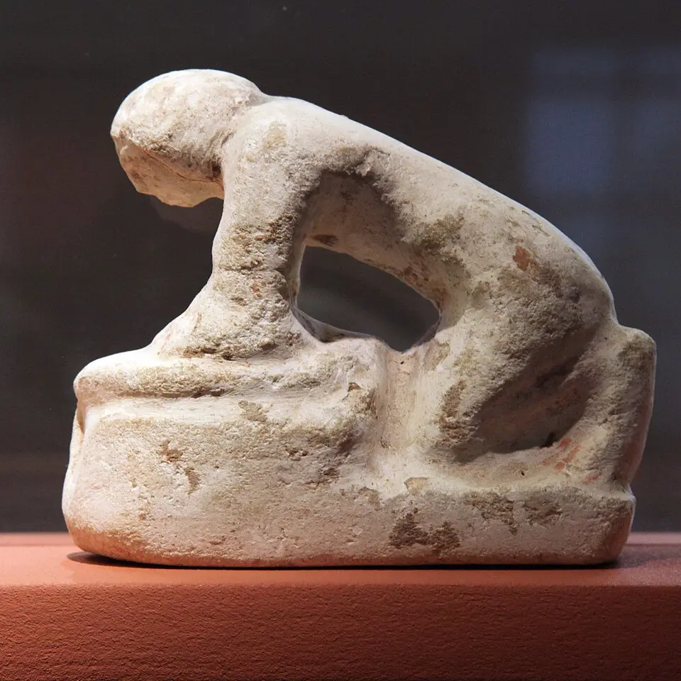 Ancient Egyptian limestone figure of a woman preparing bread dough